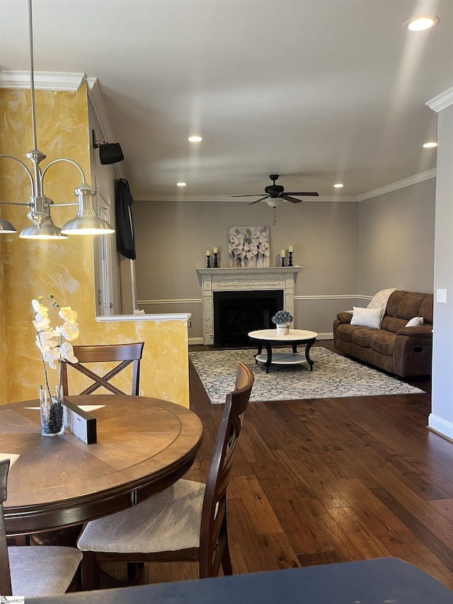 dining space featuring a fireplace, recessed lighting, wood-type flooring, ornamental molding, and a ceiling fan