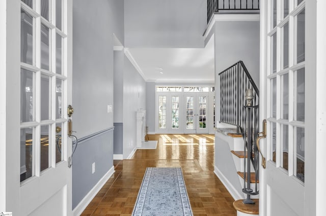 entryway with ornamental molding, french doors, a high ceiling, and baseboards