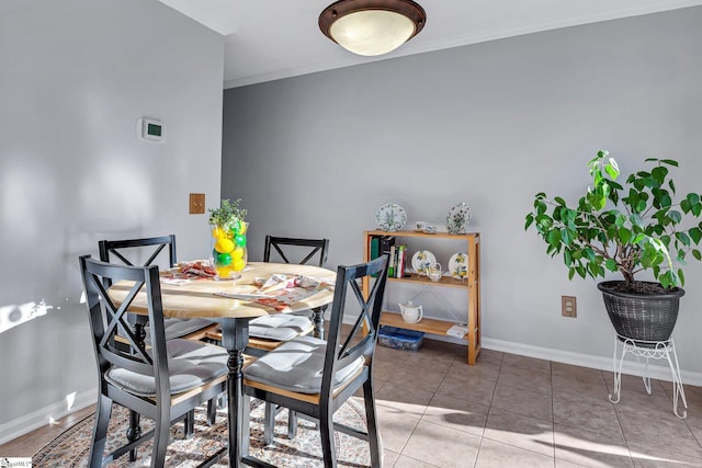 tiled dining space featuring baseboards and ornamental molding