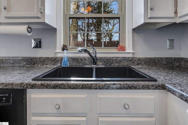 kitchen with black dishwasher, dark countertops, white cabinetry, a sink, and plenty of natural light