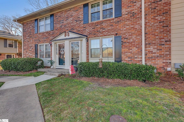 view of front facade with brick siding and a front lawn