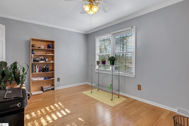 interior space featuring light wood-type flooring, crown molding, and a textured ceiling