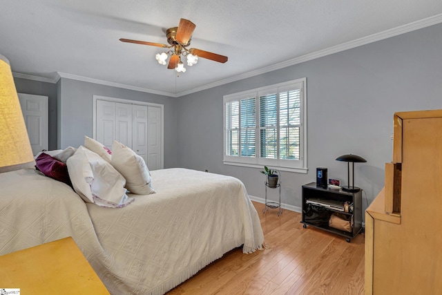 bedroom featuring baseboards, a ceiling fan, light wood-style flooring, ornamental molding, and a closet