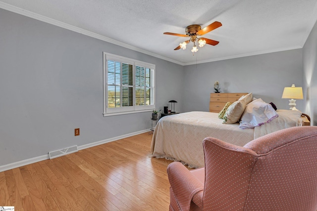 bedroom featuring baseboards, light wood-style flooring, visible vents, and crown molding