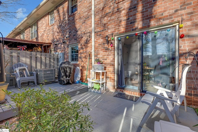 exterior space featuring brick siding, fence, central AC, and a patio