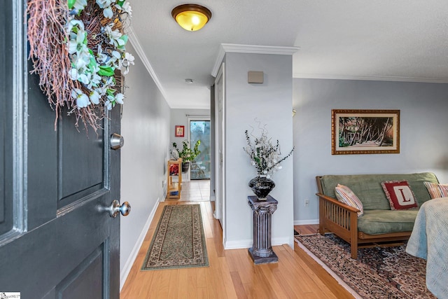 entrance foyer featuring baseboards, light wood finished floors, a textured ceiling, and crown molding