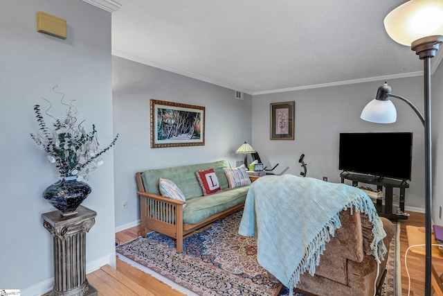 living area with baseboards, visible vents, ornamental molding, and wood finished floors