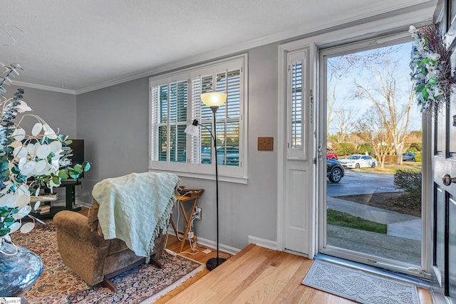 entryway with baseboards, a textured ceiling, ornamental molding, and wood finished floors