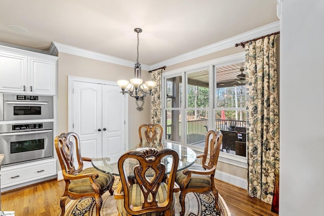 dining area with a chandelier, crown molding, baseboards, and wood finished floors