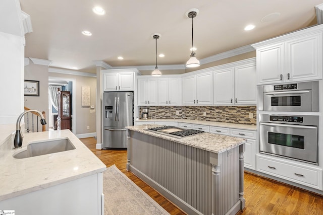 kitchen with appliances with stainless steel finishes, white cabinets, a sink, and light stone countertops