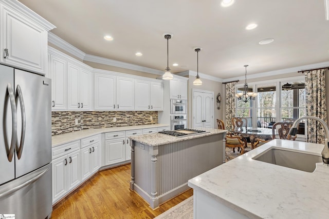 kitchen featuring a kitchen island, stainless steel appliances, white cabinetry, pendant lighting, and a sink