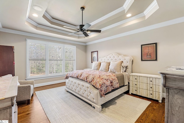 bedroom with dark wood-style floors, a raised ceiling, and crown molding