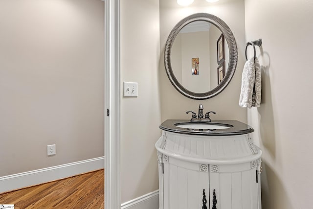 bathroom with a sink, baseboards, and wood finished floors