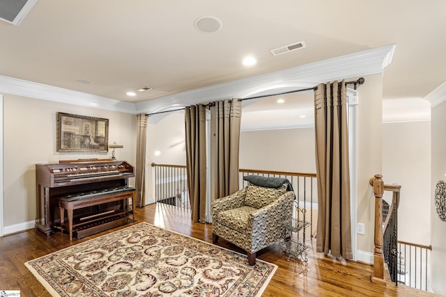 living area featuring visible vents, baseboards, dark wood-style floors, decorative columns, and crown molding