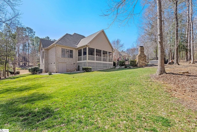 rear view of house featuring brick siding, a lawn, and a sunroom