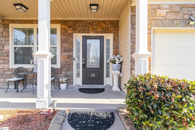 entrance to property with a garage, stone siding, and covered porch