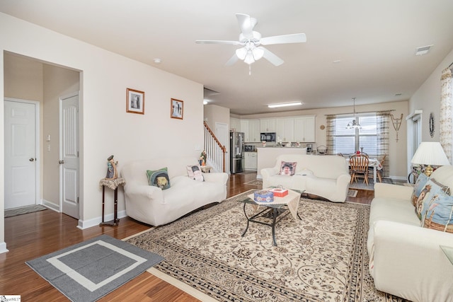 living area featuring ceiling fan, dark wood-type flooring, visible vents, baseboards, and stairs