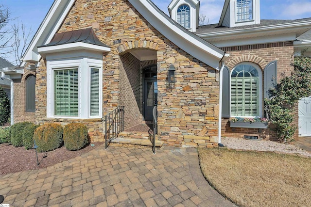 view of exterior entry featuring stone siding, crawl space, and brick siding