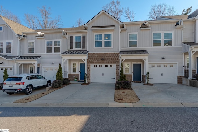 townhome / multi-family property with metal roof, an attached garage, brick siding, concrete driveway, and a standing seam roof