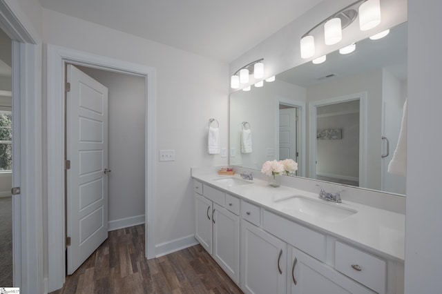 bathroom with wood finished floors, a sink, baseboards, and double vanity