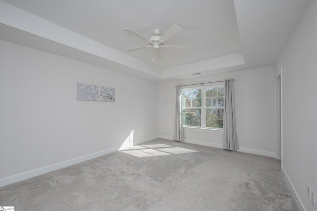 unfurnished room featuring light carpet, visible vents, baseboards, a raised ceiling, and ceiling fan