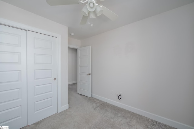 unfurnished bedroom featuring a closet, light colored carpet, ceiling fan, and baseboards