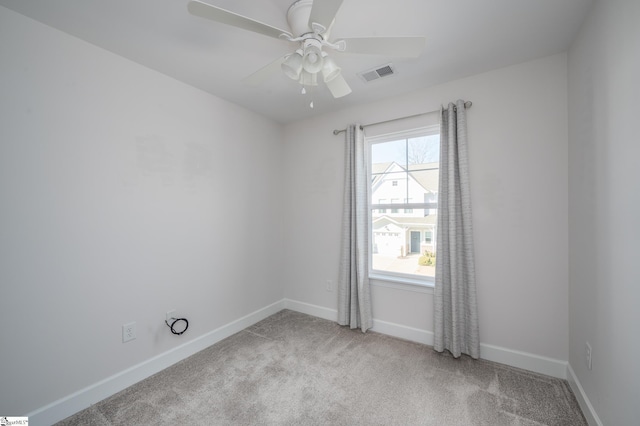 spare room with ceiling fan, light colored carpet, visible vents, and baseboards