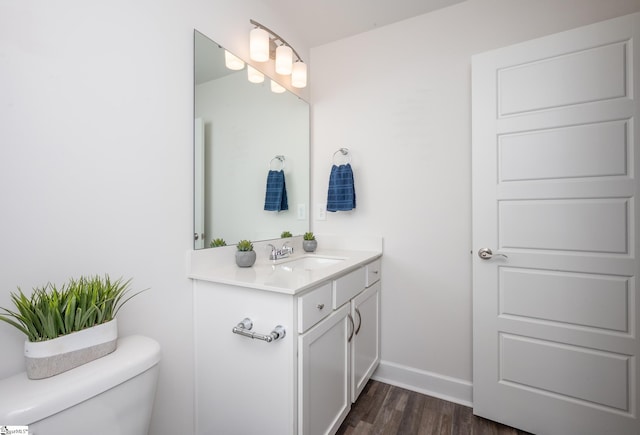 bathroom with baseboards, vanity, toilet, and wood finished floors