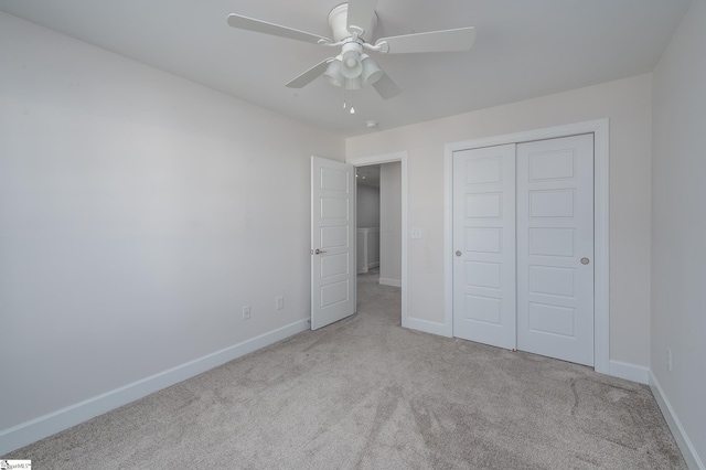 unfurnished bedroom with light carpet, a closet, a ceiling fan, and baseboards