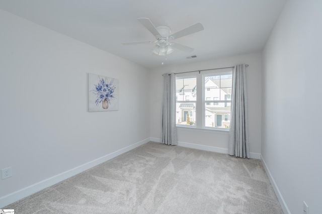 spare room featuring baseboards, ceiling fan, visible vents, and light colored carpet