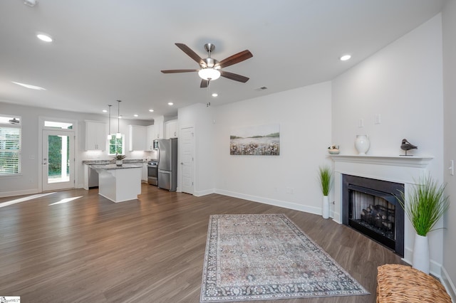 living area featuring recessed lighting, a fireplace, dark wood finished floors, and baseboards