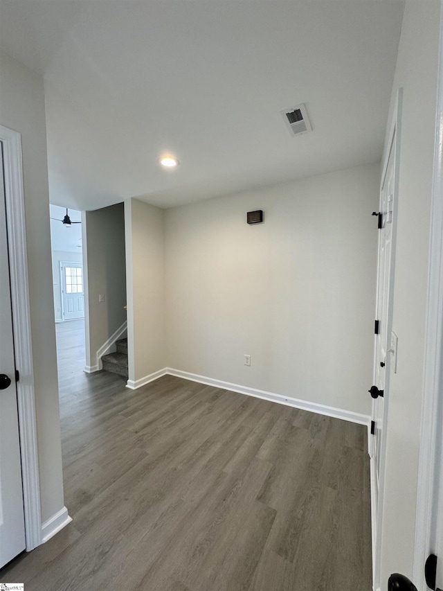 spare room with visible vents, stairway, baseboards, and wood finished floors