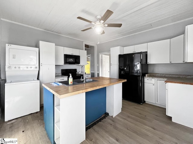 kitchen with an island with sink, black appliances, white cabinetry, and stacked washer / drying machine