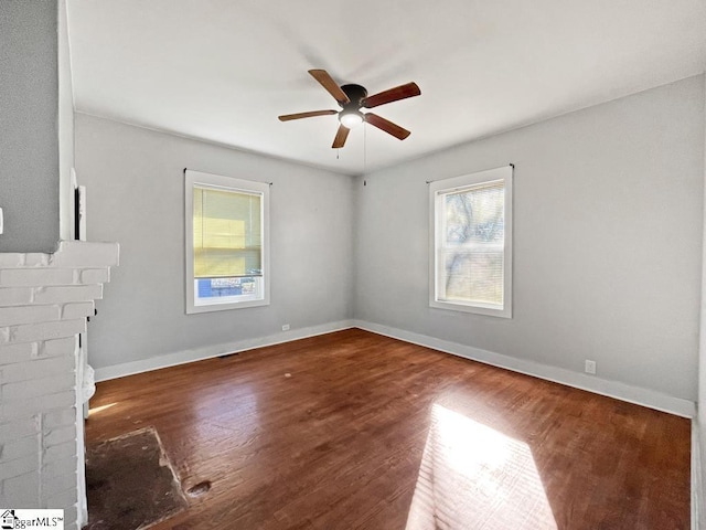 unfurnished living room with a fireplace, wood finished floors, a wealth of natural light, and baseboards