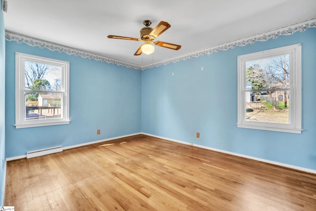 empty room with a baseboard heating unit, light wood-style floors, and a healthy amount of sunlight