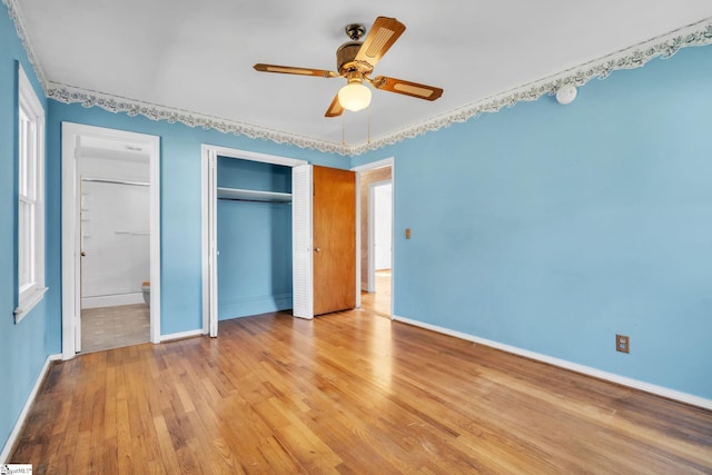 unfurnished bedroom featuring light wood-type flooring, a ceiling fan, baseboards, and connected bathroom