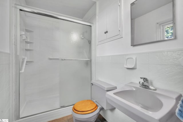 full bath with toilet, a wainscoted wall, a sink, tile walls, and a stall shower