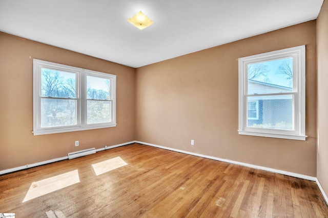 unfurnished room featuring light wood-type flooring, baseboards, and a baseboard heating unit