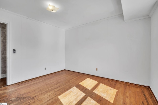 empty room with wood finished floors and crown molding