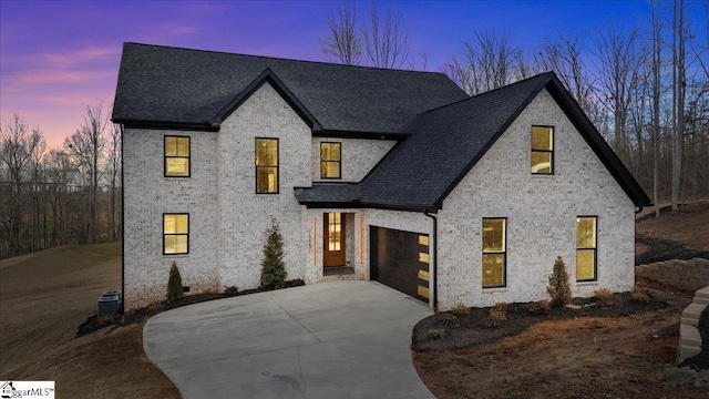 view of front of property with roof with shingles, driveway, brick siding, and central AC unit