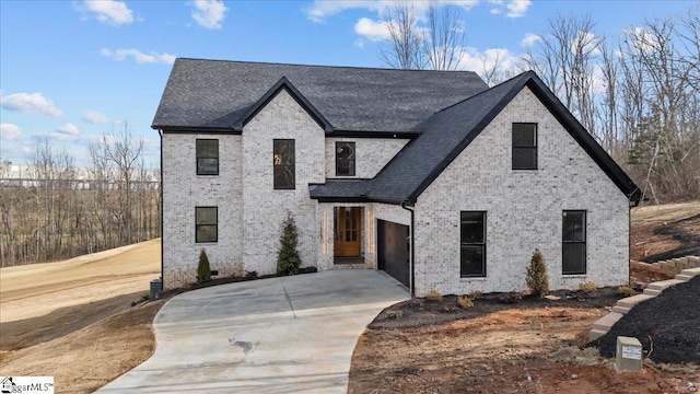 view of front of home featuring brick siding, concrete driveway, and roof with shingles