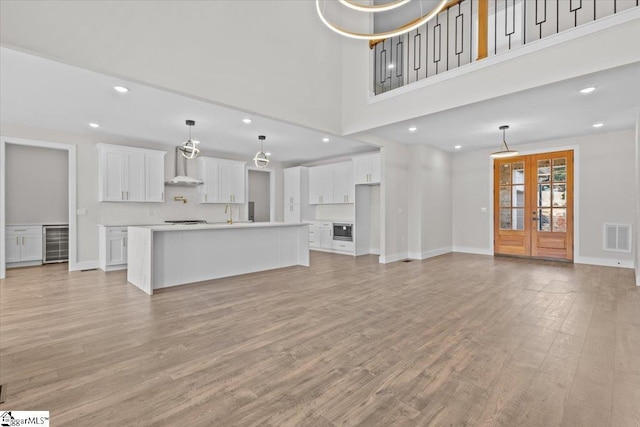 unfurnished living room featuring french doors, light wood-style flooring, visible vents, and baseboards