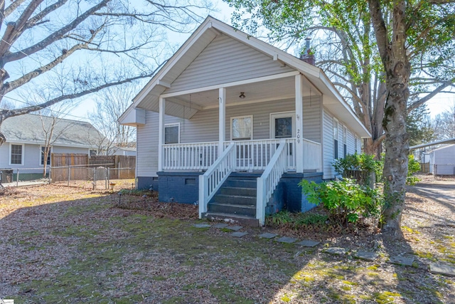 bungalow-style house with covered porch, fence, and crawl space