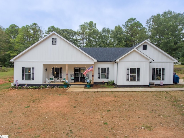 modern farmhouse with covered porch, a front yard, and roof with shingles