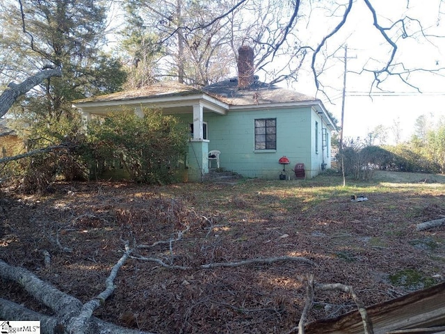 view of home's exterior featuring concrete block siding and a chimney