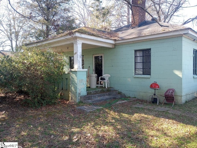 exterior space featuring a chimney and concrete block siding