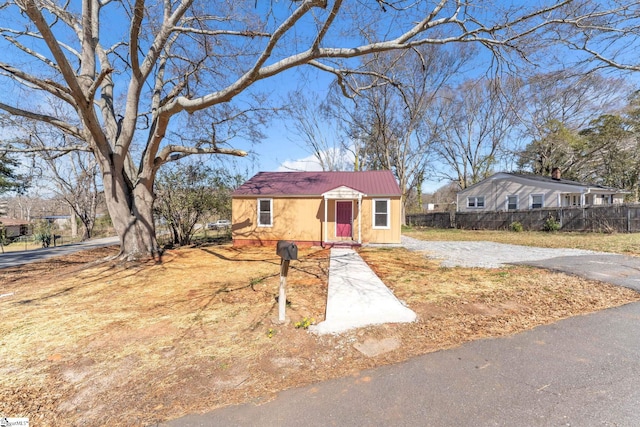 view of front of house with metal roof, fence, and driveway