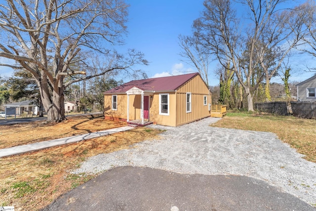 view of front facade featuring aphalt driveway, metal roof, and fence