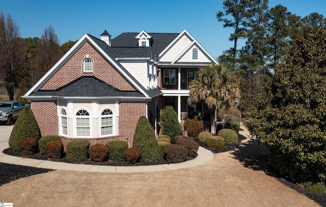 view of front of house with a shingled roof and brick siding