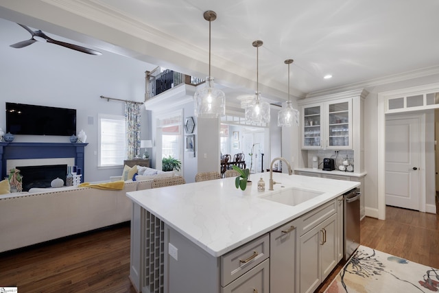 kitchen featuring open floor plan, a sink, hanging light fixtures, and a center island with sink